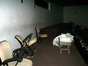 Na única sala que havia sido entregue, cadeiras quebradas e sujeira predominam entre o breu.